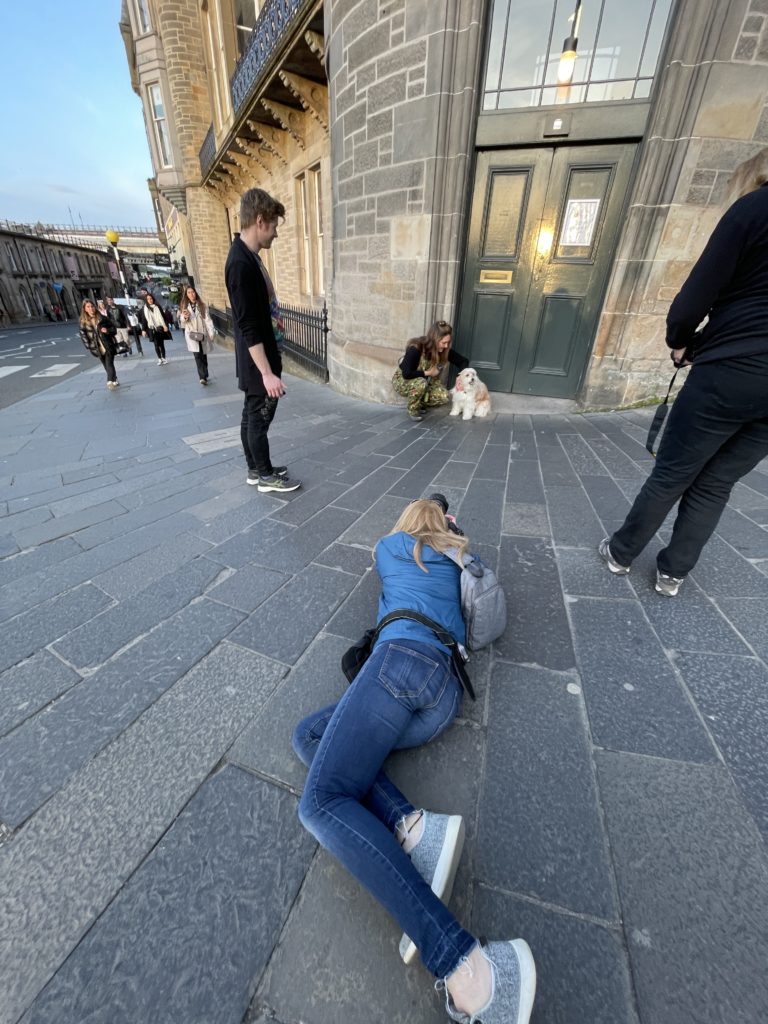 woman taking a picture of a woman and a dog in front of a green door