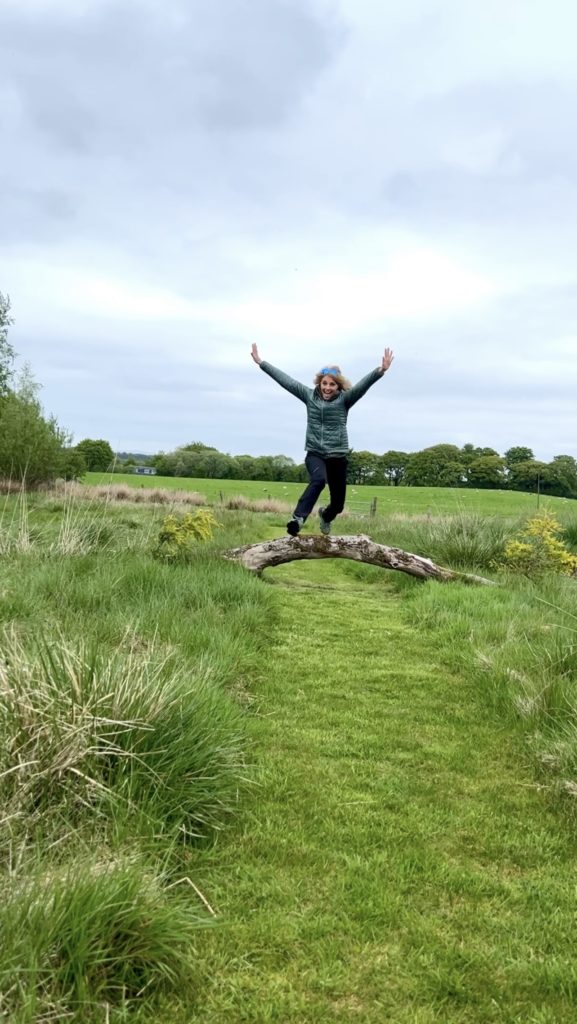 woman jumping over a log