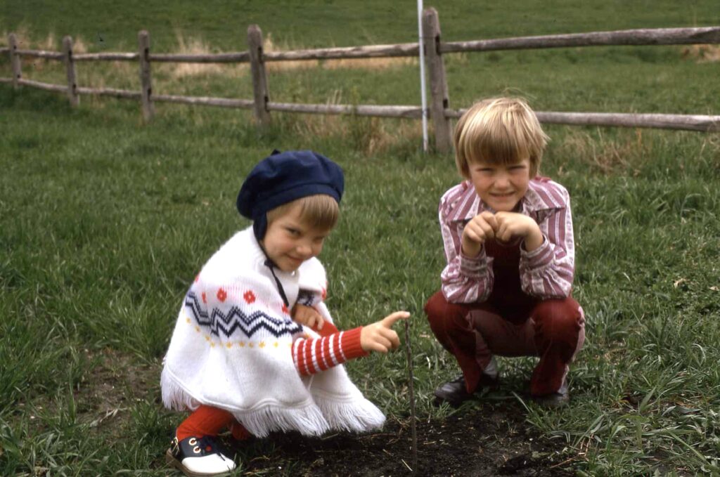 image of a small girl and boy in the 1970s in front of a fence