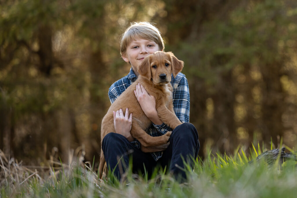 golden retriever puppy being held by a blonde boy